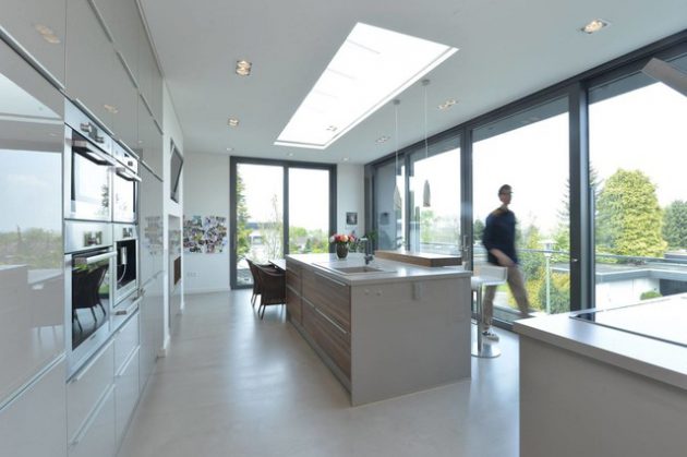 fenêtre de toit de style verrière dans une cuisine de style moderne avec ilot central et table de repas