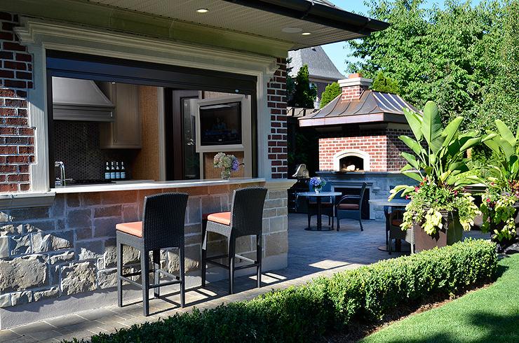Cuisine en pierre naturelle avec bar ouverte sur la terrasse avec son four à bois En voilà une cuisine d'été qui a du style!
