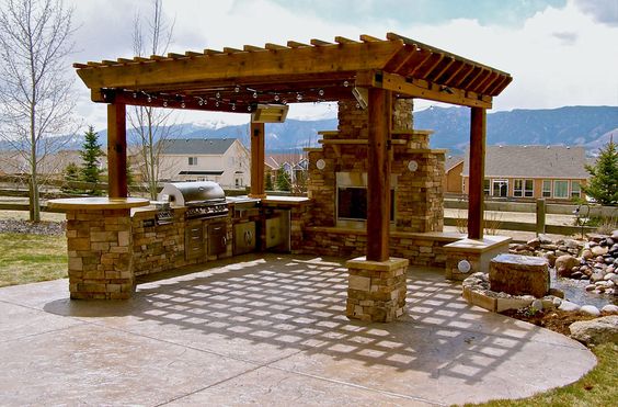 Une pergola en bois pour abriter une cuisine d'été en moellon de granit Cuisine moderne sous une pergola pour profiter du soleil et du jardin.