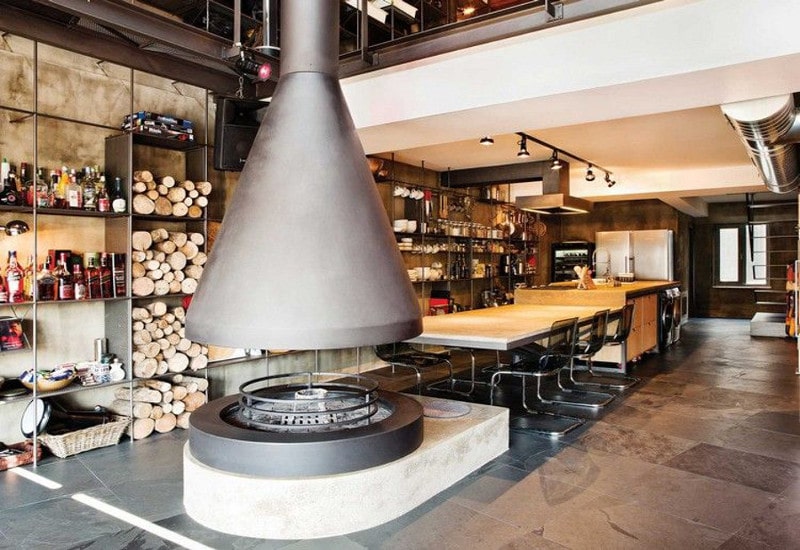 grande cuisine industrielle dans un loft qui accueille un poêle immense en fonte L'idée d'installer un poêle géant au milieu de la pièce est plutôt originale.