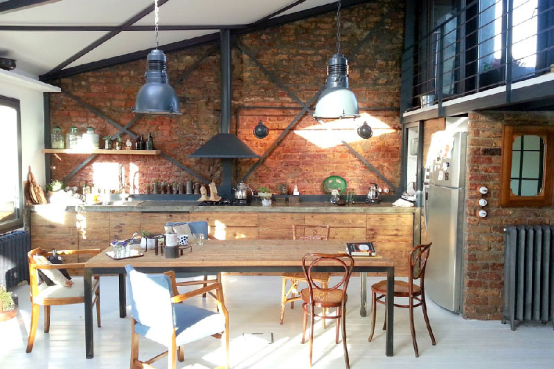 cuisine dans un loft de style rustique et industriel. On aime les lampes bleu et la présence de briques