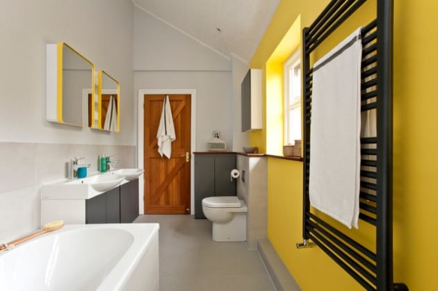 Salle de bains blanche tout en longueur composée d'un mur jaune clair pop. Deux miroirs accrochés avec deux vasques en dessous et baignoire à proximité. le-jaune-dans-la-salle-de-bain
