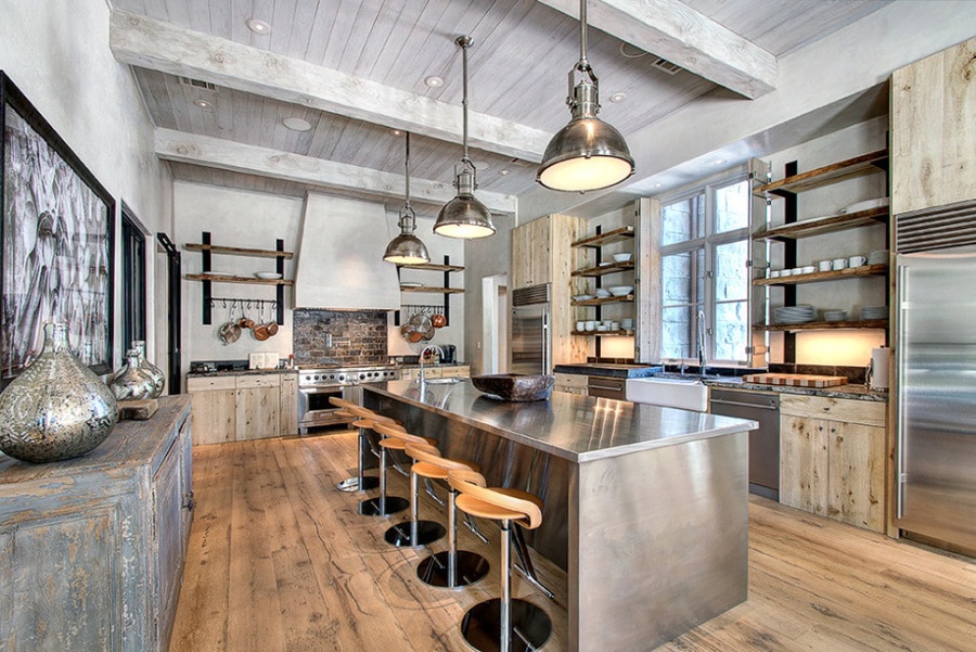 Trucs déco pour donner à votre cuisine un air de campagne comme du parquet, des étagères en bois, un mur en pierres ou encore un style industriel. Trois lampes suspendues au-dessus d'un plan de travail en I. L'art de mélanger la décoration de campagne et le loft. Source : https://www.parkerhousehouston.com/
