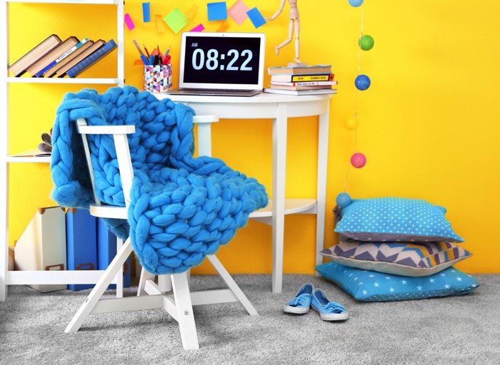 Chambre d'ado garçon style pop tout en jaune avec moquette grise. Bureau blanc avec couverture en nœuds couleur bleu-clair, coussins à pois blancs et post-it colorés. deco-chambre-ado-garcon-copyright-africa-studio-7