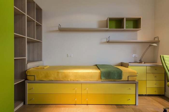 Chambre d'ado garçon originale décorée style pop et colorée. Quatre tiroirs jaunes sous un lit une place sur parquet, rangements en bois sur le côté gauche. deco-chambre-ado-garcon-copyright-basileus-02