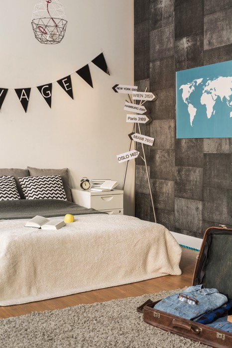 Chambre d'ado garçon originale décorée avec mur blanc, mur gris et parquet avec tapis gris. Lit deux places avec divers coussins, décoration géographique dotée d'une carte du monde et panneaux avec capitales. deco-chambre-ado-garcon-photographee-eu-078