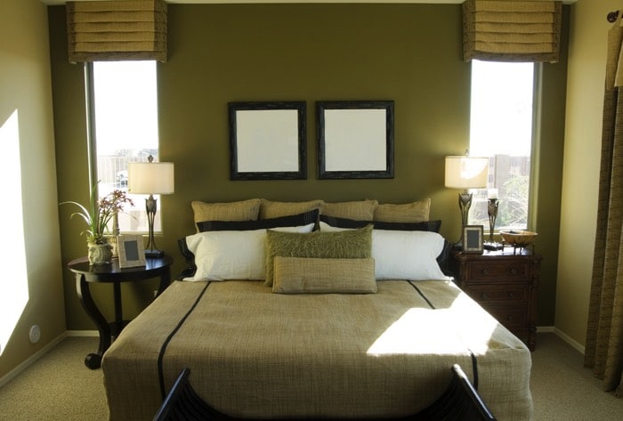 Chambre avec association parfaite entre le lin et la couleur verte, deux miroirs carrés au-dessus d'un grand lit. Peinture dans des tons naturels apportant sérénité et détente.