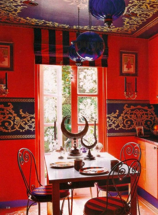 Salle à manger boho-chic à l'aspect fortement spirituel avec couleurs orange et violette. Plafond à motifs repris sur le mur, pièce servant pour de la voyance.