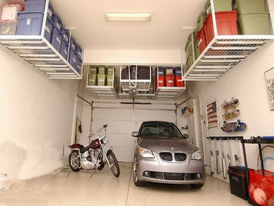 Garage aménagé classique avec étagères blanches en hauteur accrochés au plafond. Skateboards accrochés au mur, magnifique BMW et moto.