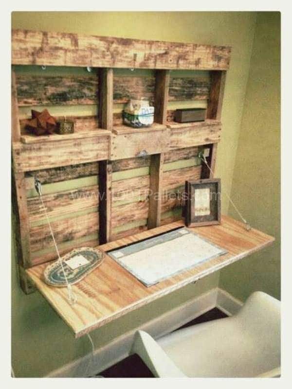Bureau palettes rabattable avec deux niveaux de rangement supérieurs et plusieurs accessoires posés dessus. Siège tout blanc.