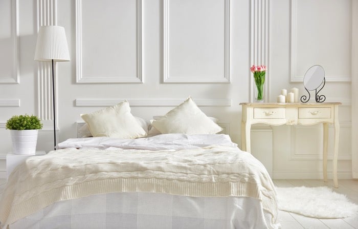 Chambre blanche avec lit deux places dans une ambiance pop ethnique chic. Table de chevet style gustavien avec petit miroir dessus.