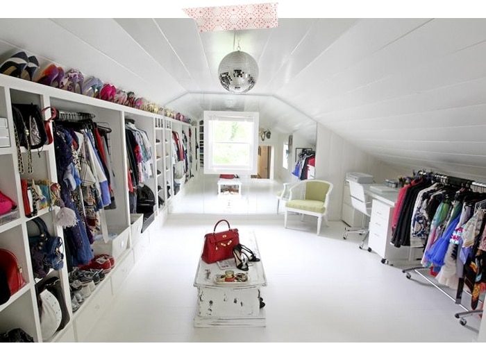 Dressing dans les combles tout en blanc avec multitude de rangements en étagères sur la gauche et boule disco au plafond. Bureau sur la droite et vieille table basse en plein milieu. dressing dans les combles 1