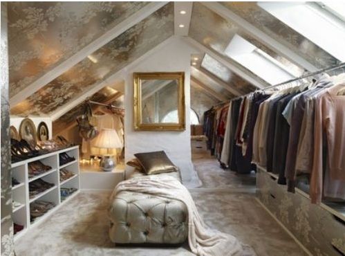 Dressing dans les combles style moderne industriel avec fenêtres et miroir sur mur blanc. Étagère blanche sur la gauche avec chaussures rangés et vêtements sur la droite.