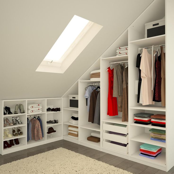 Dressing dans les combles blanc avec fenêtre rectangulaire et parquet avec tapis beige. Rangements carrés et rectangulaires remplis de vêtements, draps, chaussures et robes.