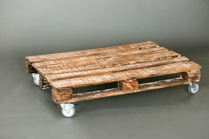 Fabrication d'une table basse en vieux bois usé dotée de cinq planches au-dessus avec quatre roulettes noires en acier. fabriquer-table-basse-palette-279photo-studio-3