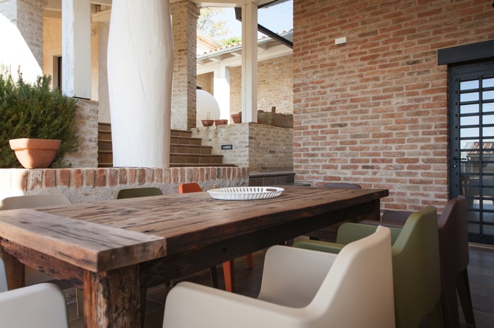 Table de salle à manger en extérieur. Chaises de différentes couleurs (orange, vert clair et blanc) sur carrelage et parquet.