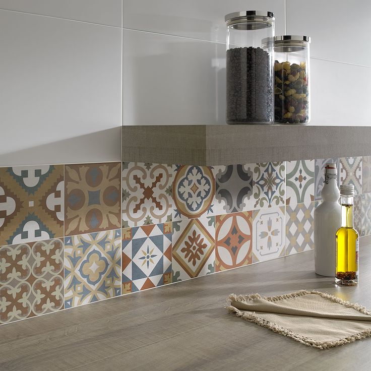 Divers carreaux à motifs pour carrelage mural au-dessus d'un plan de travail en bois. Étagère avec deux grands pots en verre et carrelage mural blanc en haut.