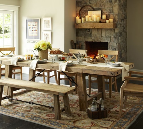 Salle à manger campagnarde blanche avec cheminée en pierre et carrelage gris. Table rectangulaire en bois avec chaises et blanc sur magnifique tapis au style oriental.
