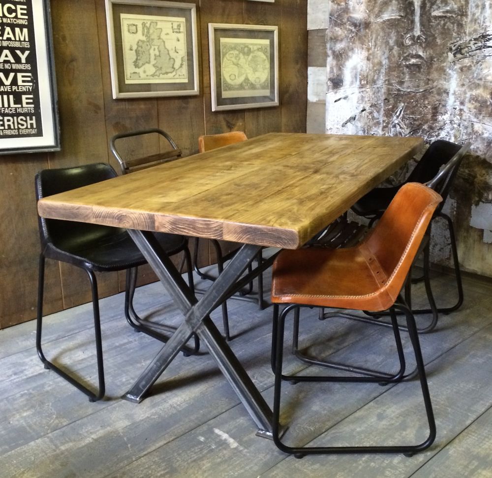 Salle à manger style industriel avec table rectangulaire en bois, chaises et parquet. Deux tableaux de cartes géographiques et magnifique représentation abstraite d'un visage à gauche.