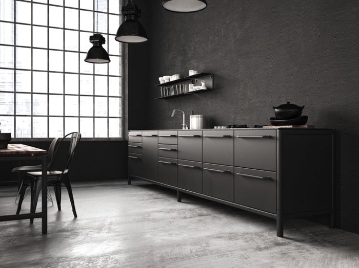 Salle à manger type industriel en anthracite avec trois lampes noires suspendues. Plan de travail en L avec multitude de rangement inférieurs sur parquet. Table à gauche.
