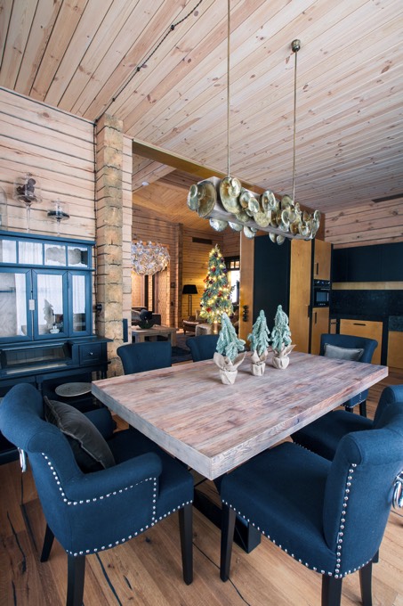 Idée déco pour moderniser une salle à manger traditionnelle avec table en bois frêne rectangulaire et fauteuils de couleur bleu. Lampe originale suspendue et meuble en verre sur le côté.