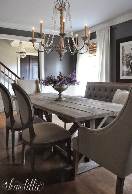 Salle à manger traditionnelle moderne avec table rectangulaire en bois blanc, fauteuil et deux chaises. Deux magnifiques lustres différentes en verre, tableau à droite et pot de fleurs sur la table.