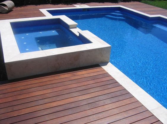 Aménager une piscine ultra moderne en bois wengé avec petit escalier dans un angle. Jacuzzi juste à côté du même style que la piscine.