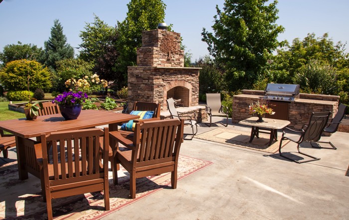Une terrasse en béton avec table en bois et coin barbecue pour la cuisine extérieure de jardin