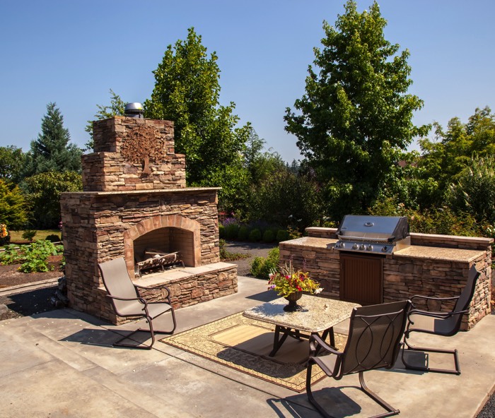 Cuisine d'extérieur en pierre naturelle avec barbecue en inox et chaises en aluminium