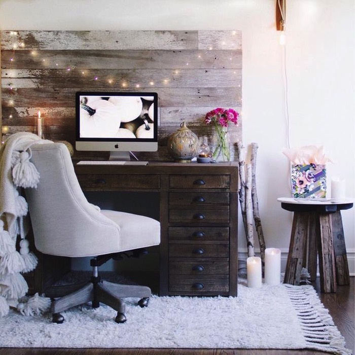 Aménagement d'un petit bureau en bois wengé avec une multitude de tiroirs. Siège blanc, petit table en bois, PC moderne , fleurs et tapis blanc sur parquet.
