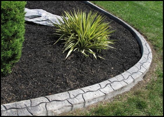 Pose d'une bordure béton avec petit effet de lignes arrondies. Délimitation avec la pelouse et un espace jardin avec cactus et plantes grasses.