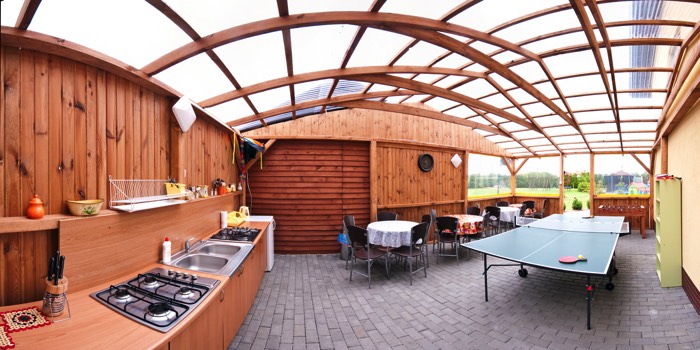 Grande verrière en bois et en verre pour abriter une cuisine de jardin d'été tout équipée