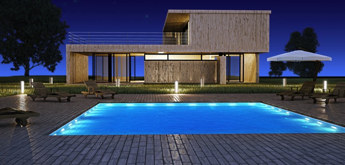 Aménagement d'une piscine carré avec spots intégrés. Multitude de lumières originales autour avec transats en bois, pelouse et maison au style architectural ultra moderne.