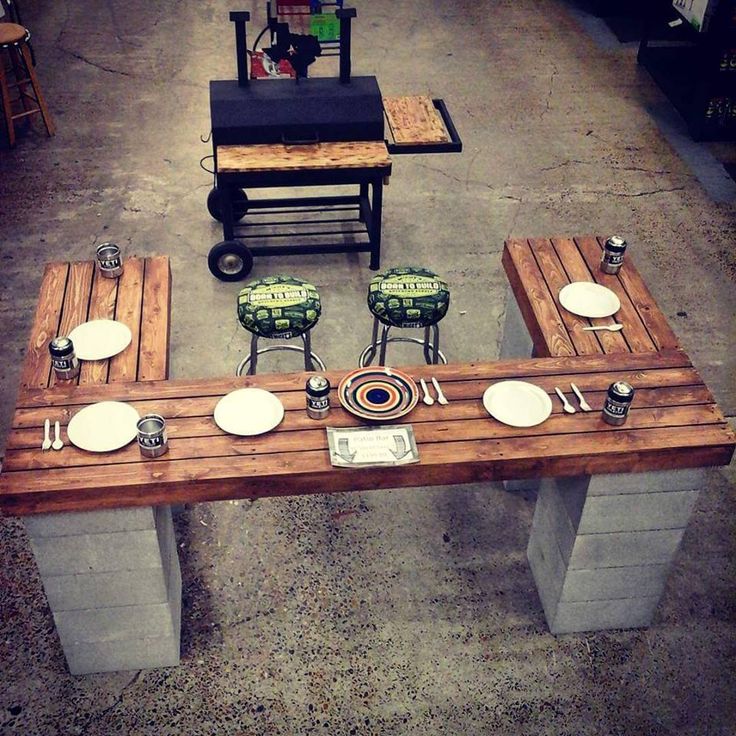 Des parpaings décoratifs permettant de maintenir la table en bois fait de palettes, en hauteur. Tabourets de bar originaux et verts.