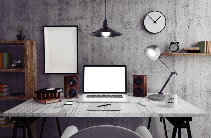 Aménagement d'un bureau blanc rectangulaire dans une pièce moderne style industriel. PC moderne avec deux petites enceintes en bois, cadre blanc minimaliste, horloge sur mur gris.