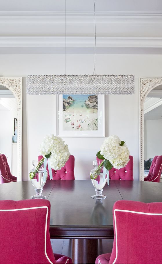 Salle à manger à couleur blanche relevée par les chaises fushia. Ceci donne une atmosphère pop.