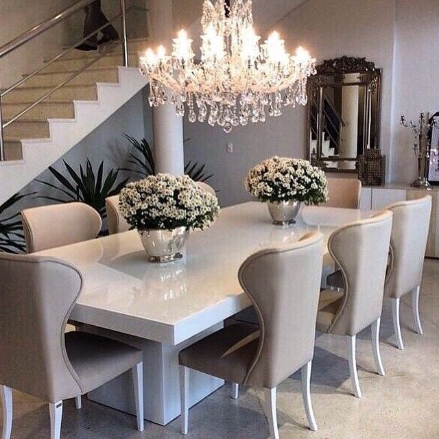 Salle à manger moderne dont la couleur principale est la couleur taupe. Un magnifique lustre est suspendu au dessus de la table.
