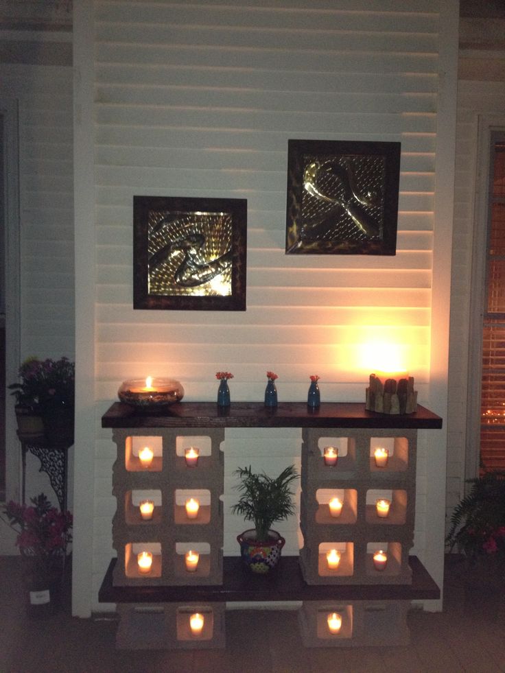 Parpaings creux avec des petites bouges dedans. Étagère avec deux planches en bois et deux tableaux carrés en hauteur.