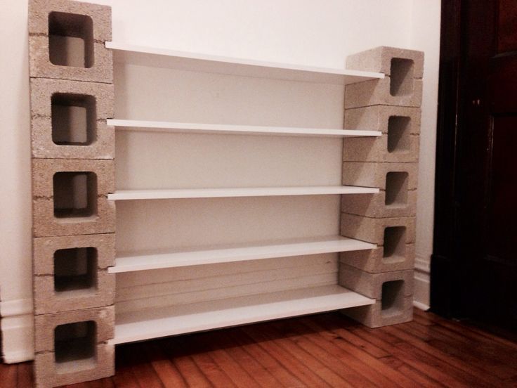 Idée parpaings intérieurs bruts pouvant servir de rangement. Étagère à planches blanches sur mur blanc et parquet en bois noyer.
