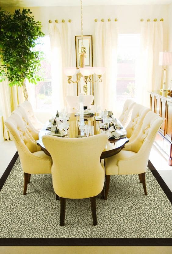 Salle à manger jaune or avec grand tapis et rideaux. Table à manger en bois avec fauteuils jaunes et magnifique lustre en or.