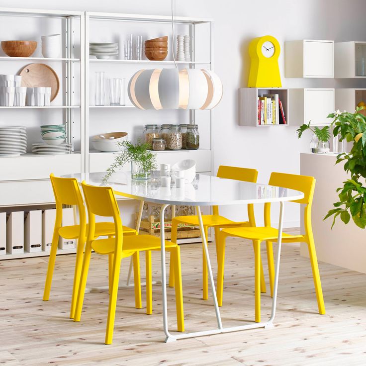 Salle à manger pop moderne jaune et blanche. Table à manger avec quatre chaises jaunes, horloge jaune et lampe suspendue.