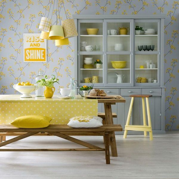 Salle à manger pop jaune avec sol en bois frêne. Table à manger en bois avec nappe jaune et petits pois blancs, tapisserie avec fleurs jaunes.