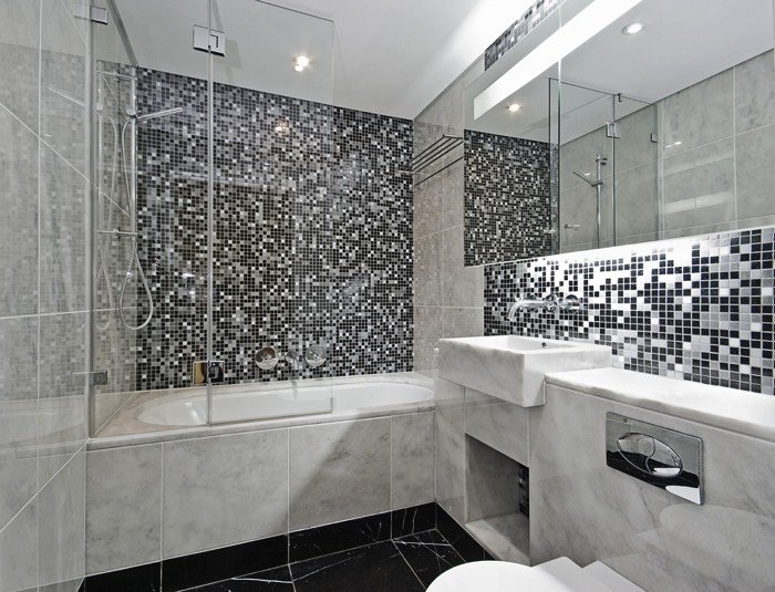 baignoire avec colonne de douche apparent et mur en mosaïque noir et blanc