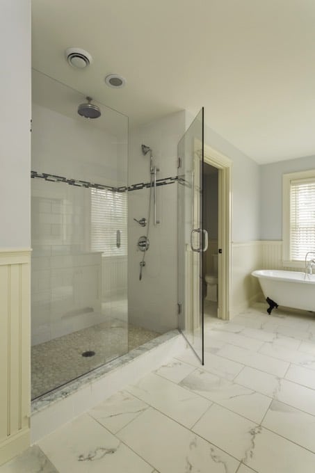 Salle d'eau style industriel avec douche classique dotée d'une porte de verre transparent. Colonne de douche hydromassante avec pommeau de douche rond.