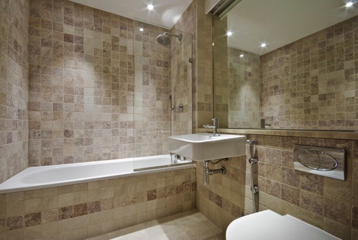 Colonne de douche classique pour baignoire blanche avec paroi en verre transparente. Grand miroir et spots lumineux dans une ambiance ethnique et ancienne avec carrelage mural ancien.