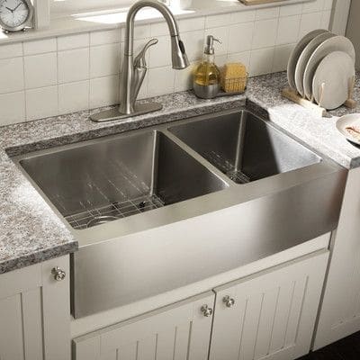 Évier à poser gris en inox avec 2 bacs et robinet mitigeur. Carrelage mural blanc.
