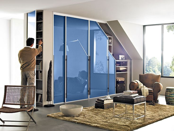 Placard sous pente bleue doté de portes miroirs. Salon style industriel avec grand tapis beige et fauteuil.
