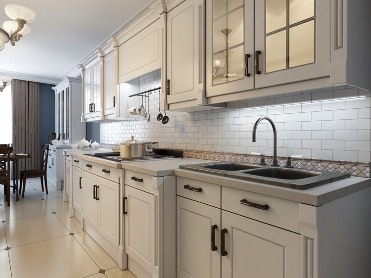 Cuisine blanche avec rangements en hauteur. Un évier à deux bacs encastré sous plan en marbre.
