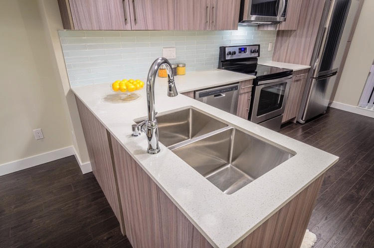 Double évier sous plan en inox avec plan de travail cuisine en L blanc et en bois. Cuisine avec parquet.