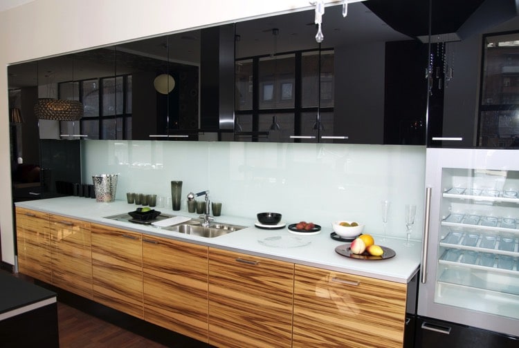 Plan de travail de cuisine en bois stratifié et en blancPlan de travail de cuisine en bois stratifié et en blanc avec multiples rangements noirs en hauteur. Petit frigo blanc à côté du plan de travail. avec rangements noirs en hauteur